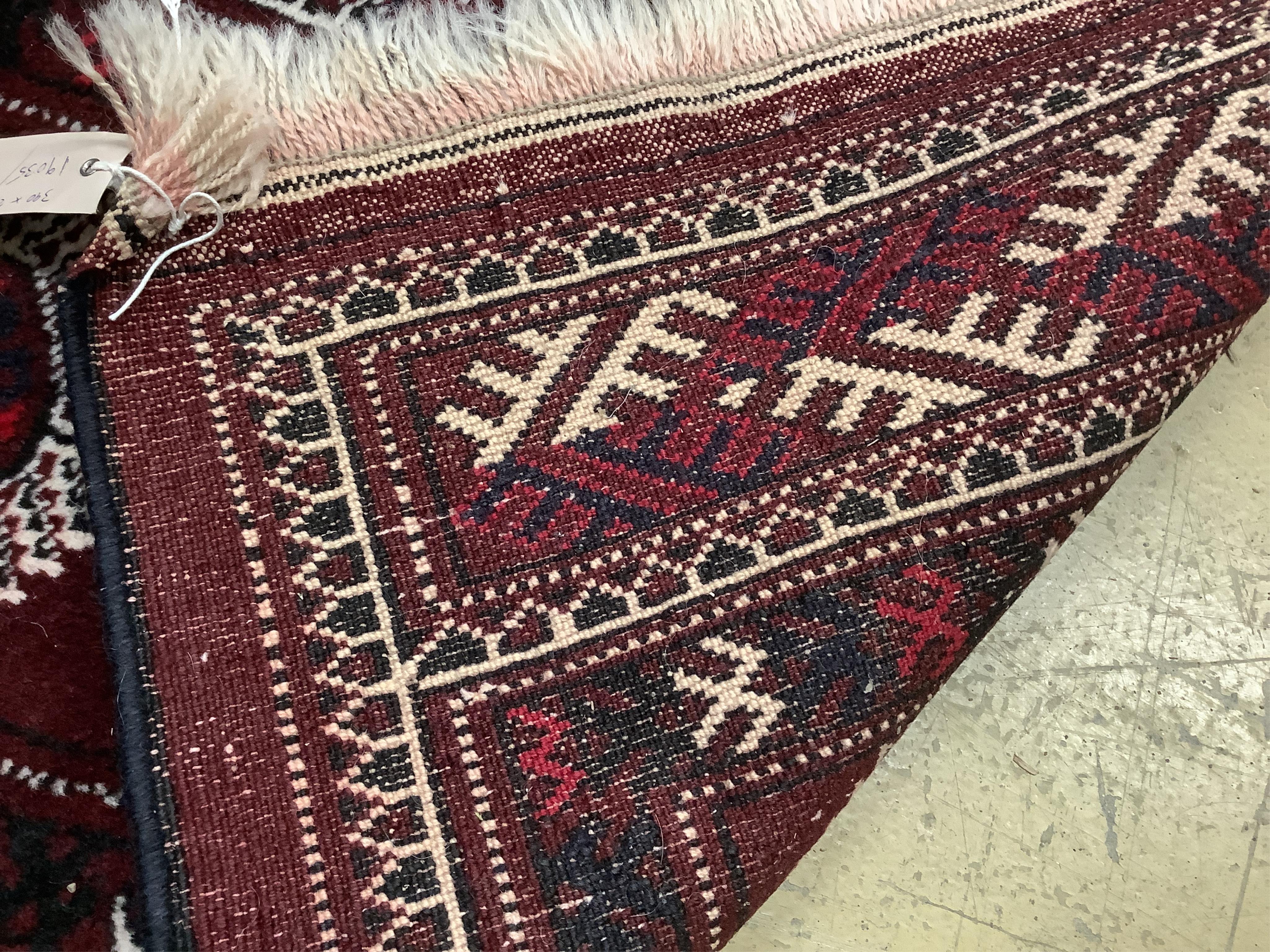 A Turkoman burgundy ground carpet, 386 x 234cm